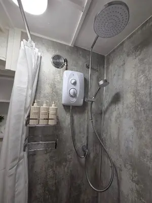 a shower with a shower head in a bathroom at Cosy Cornwall Cottage with Private Garden in Bodmin