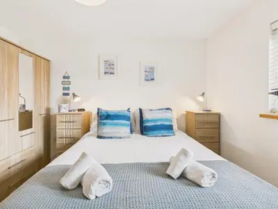 a bedroom with a bed with blue and white pillows at 1 Arvor – Two-Bedroom Apartment with Parking at Maenporth Beach! Cornwall in Falmouth