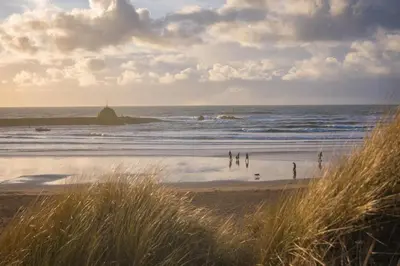a group of people on a beach near the ocean at 2 Bed in Widemouth Bay oc-s34972 in Widemouth Bay