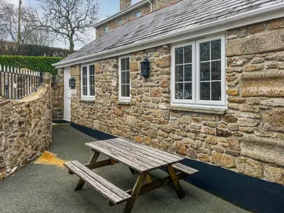 a wooden bench sitting outside of a stone building at Henhouse - Uk49016 in Liskeard