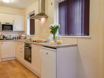 a kitchen with white cabinets and a vase of flowers on the counter at Milking Parlour - Uk49026 in Liskeard