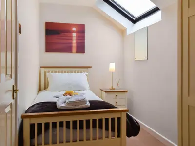 a small bedroom with a bed and a window at Cowshed - Uk49024 in Liskeard