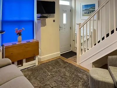 a living room with a staircase with a blue wall at Seagull Cottage in Looe