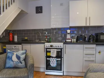 a kitchen with a stove top oven next to two chairs at Seagull Cottage in Looe