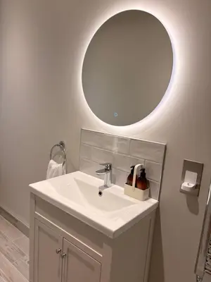 a bathroom with a sink and a round mirror at Porthtowan Guest Suite in Porthtowan
