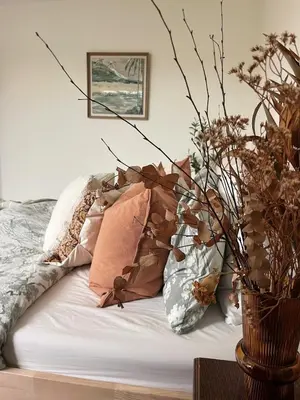 a bed with pillows and a vase with flowers at SeaNest and cabin, walk to beach in St. Agnes