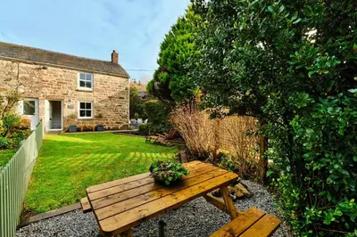 a wooden picnic table in the garden of a house at Finest Retreats - Mill Stone Cottage in Nancledra