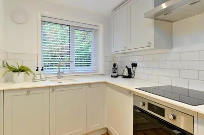 a kitchen with white cabinets and a sink and a window at Finest Retreats - Mill Stone Cottage in Nancledra