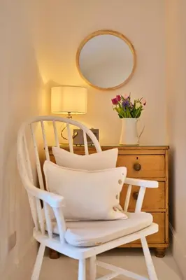 a white rocking chair next to a dresser with a mirror at Finest Retreats - Mill Stone Cottage in Nancledra