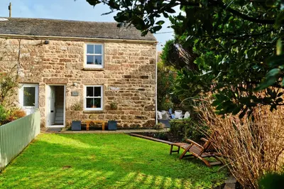 a stone cottage with benches in the yard at Finest Retreats - Mill Stone Cottage in Nancledra