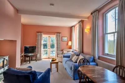 a living room with a blue couch and a tv at Finest Retreats - Captains Cottage at Mixtow Creek in Lanteglos