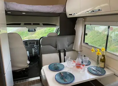 a table in the back of a van with plates and glasses at Raffy The Motorhome in St Merryn