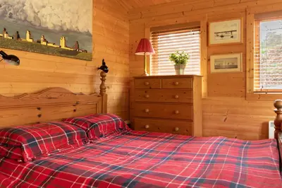 a bedroom with a bed with a red plaid blanket at The Cabin at Little Bosveal near the Helford River....lovely location in Mawnan Smith
