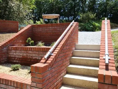 a brick retaining wall with stairs in a yard at The Cabin at Little Bosveal near the Helford River....lovely location in Mawnan Smith