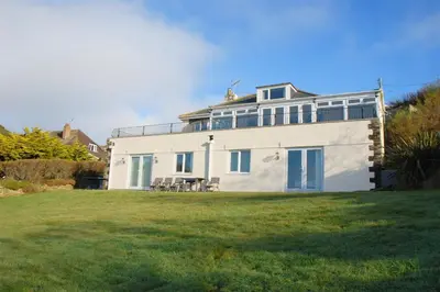 a large white house with a lawn in front of it at Atlantic View Mawgan Porth with sea views in Saint Mawgan