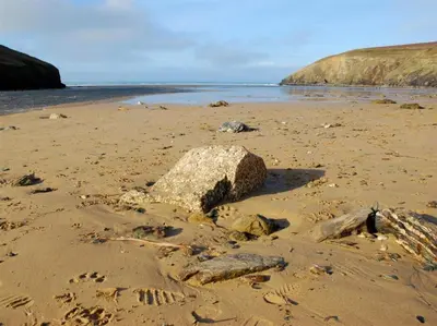 a rock on a beach with footprints in the sand at Atlantic View Mawgan Porth with sea views in Saint Mawgan