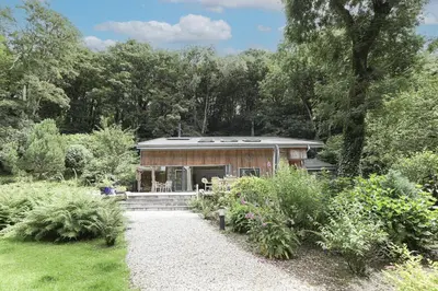 a small house in the middle of a garden at Dippers woodland setting at the Luxulyan Valley in Luxulyan