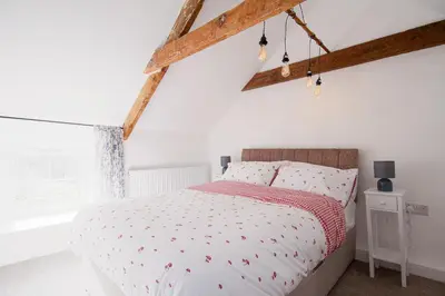 a bedroom with a bed with white walls and wooden beams at Tramanda a rural retreat to explore Bodmin Moor in Blisland
