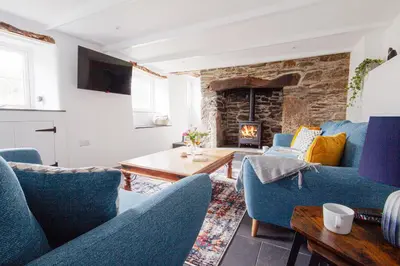 a living room with blue chairs and a fireplace at Tramanda a rural retreat to explore Bodmin Moor in Blisland