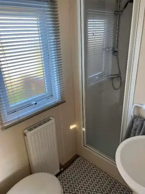 a bathroom with a shower and a toilet and a sink at Static Caravan 9 in Lansallos