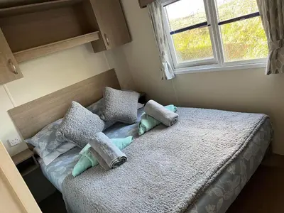 a bedroom with a bed with pillows and a window at Static Caravan 10 in Lansallos