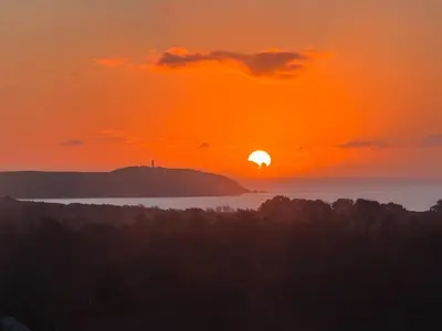 a sunset over a body of water with the sun at Barrel Cabin 2 in Trethurgy