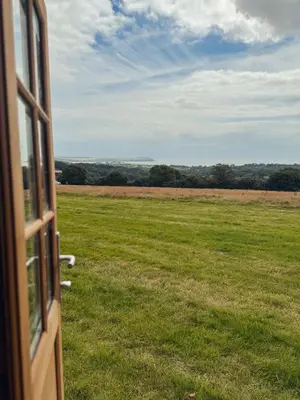 a view of a field from a open door at Barrel Cabin 2 in Trethurgy