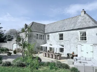 a large stone house with a patio with umbrellas at Jacobean Farmhouse, pet friendly in Truro