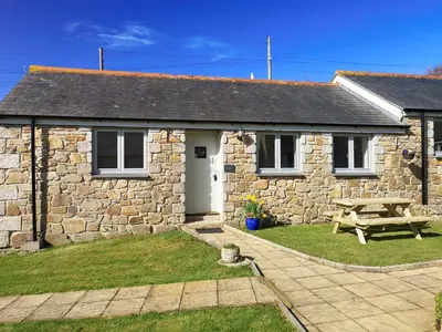 a stone cottage with a picnic table in front of it at Elm - 31304 in Porthtowan