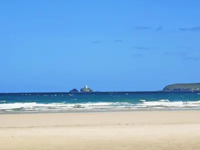 a person standing on a beach near the ocean at Elm - 31304 in Porthtowan