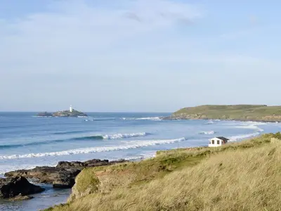 a small white house on a hill next to the ocean at Elm - 31304 in Porthtowan