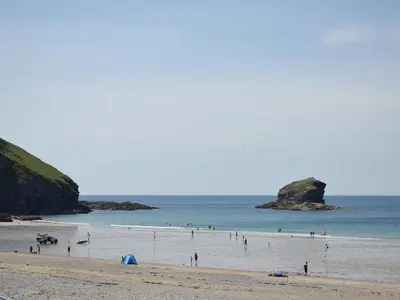 a group of people standing in the water on a beach at Elm - 31304 in Porthtowan