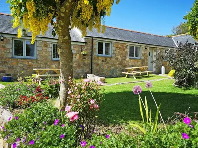 a stone house with a picnic table and flowers at Elm - 31304 in Porthtowan