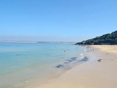 a beach with a bunch of people in the water at Driftwood in St Ives