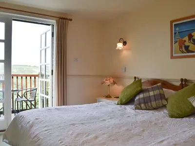 a bedroom with a bed and a balcony at Little Larnick in Looe