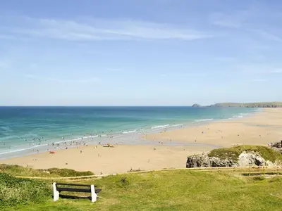 a bench on a hill overlooking a beach with people at Brambles in St. Agnes