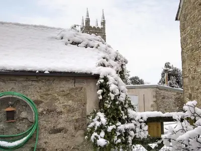 a snow covered roof of a building with a green hose at Tucked Away in Linkinhorne