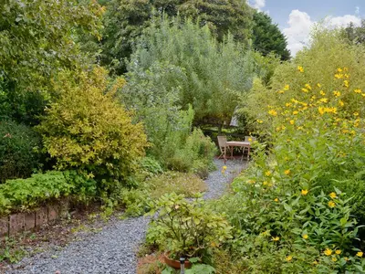 a garden with a bench in the middle of flowers at Tucked Away in Linkinhorne