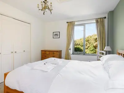 a bedroom with a white bed and a window at The Roost in Saint Breward