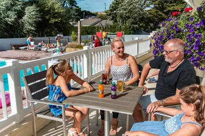 a group of people sitting around a table on a patio at Newquay Bay Holiday Resort in Newquay
