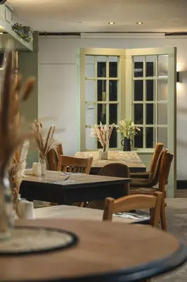 a dining room with tables and chairs and windows at The Inn For All Seasons in Redruth