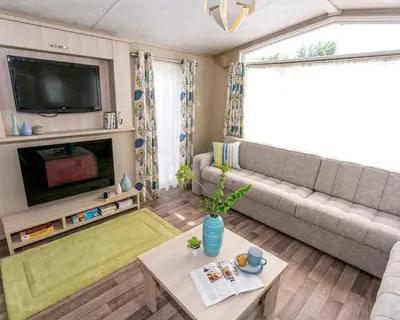 a living room with a couch and a tv at Widemouth Bay Caravan Park in Bude