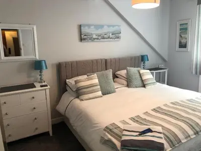 a bedroom with a bed and a dresser with a mirror at Bridgeside Guest House in Looe