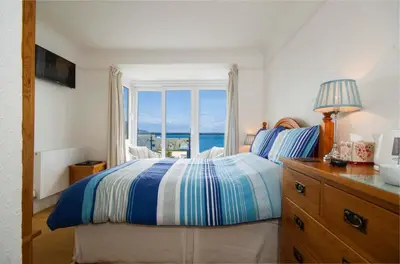 a bedroom with a bed with a view of the ocean at Seaview in Looe