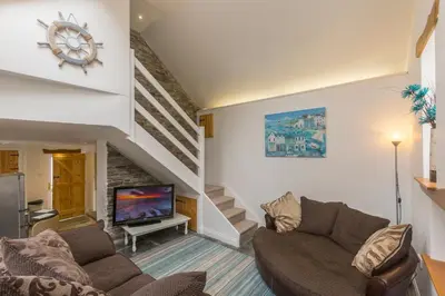 a living room with a couch and a tv at The Old Coach House in Boscastle