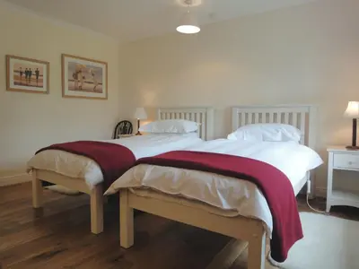 two beds in a bedroom with white walls and wood floors at Higher Tumrose in Blisland