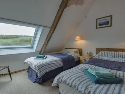 two beds in a room with a window at The Boat House in Lerryn