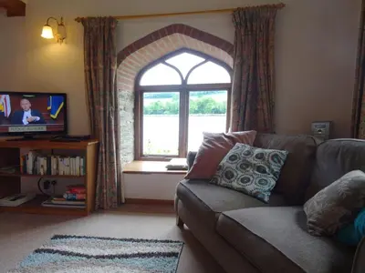 a living room with a couch and a window at The Boat House in Lerryn
