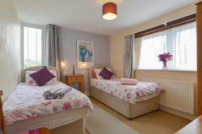 a small bedroom with two beds and a window at Regatta Cottage in Feock