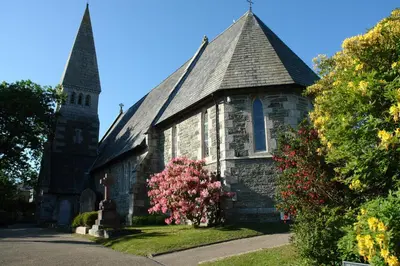 an old church with two towers and a flowering tree at Regatta Cottage in Feock